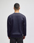 A navy crewneck sweatshirt displayed from the back, featuring long sleeves and a simple design. It has a logo.