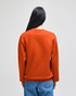 A crewneck sweatshirt in a vibrant orange colour, featuring a back view on a person wearing it.