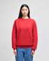 A red crewneck sweatshirt displayed on a model, featuring long sleeves and a logo.