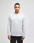 A grey crewneck sweatshirt displayed on a model, featuring a logo on one sleeve.