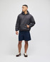 A model wears a grey crewneck sweatshirt with a hood, paired with navy shorts and casual shoes.