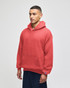 A red crewneck sweatshirt with a hood, featuring a front pocket and a logo on the sleeve.