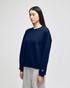 A woman wearing a navy blue Champion Powerblend® crewneck sweatshirt paired with grey bottoms, featuring a logo.