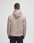A beige pullover hooded sweatshirt with a loose fit and a hood, viewed from the back.