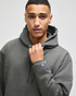 A grey pullover hooded sweatshirt on a model, featuring a logo on the sleeve.