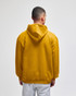 A back view of a mustard yellow hooded sweatshirt, featuring a large hood and a relaxed fit.