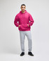 A pink pullover hooded sweatshirt with a front pocket, paired with grey sweatpants and black shoes.