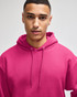 A man wearing a bright pink hoodie with a drawstring hood. The sweatshirt has a logo on it.