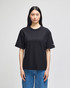 A black Champion Adult Heritage Jersey T-Shirt displayed on a model, featuring a logo on the sleeve.