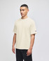 A beige Champion Adult Heritage Jersey T-Shirt on a model, featuring a logo on the sleeve.
