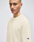 A light beige t-shirt on a model, featuring a small logo on the sleeve.