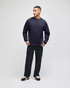 A navy blue t-shirt with long sleeves and a logo, worn by a man standing against a light background.