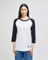 A white and black Champion Adult Raglan Baseball T-Shirt displayed on a model, featuring a logo on the sleeve.