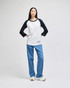 A black and white raglan baseball t-shirt paired with blue jeans, worn by a model standing against a neutral background.