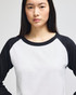 A long-sleeve raglan baseball t-shirt featuring white body and black sleeves. It has a logo on the front.