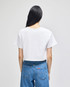 A white cropped short sleeve t-shirt displayed from the back, paired with blue jeans. The shirt features a logo.
