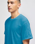 A model wearing a turquoise short-sleeve t-shirt with a relaxed fit. The shirt features a logo on the front.