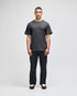 A model wearing a grey Champion adult short-sleeve T-shirt paired with black pants. The shirt features a logo.