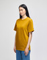 A mustard yellow short-sleeve t-shirt on a model, featuring a logo on the sleeve.