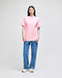 A model wearing a pink Champion short-sleeve t-shirt paired with blue jeans. The shirt features a logo.