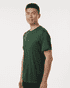 A man wearing a green performance t-shirt, featuring a fitted design and short sleeves. The shirt has a logo.