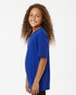 A blue youth performance T-shirt displayed on a smiling girl with curly hair, featuring a simple design and a logo.