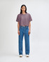 A heavyweight cotton women's crop boxy t-shirt in a muted purple, paired with blue jeans. The model stands against a plain background.