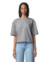 A woman stands wearing a grey mid-length boxy top, paired with light blue jeans. The top features a logo.