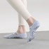 A pair of light blue yoga toe socks with a textured grip sole, worn by a person in fitted pants.