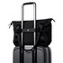 A black tote bag perched on top of a grey suitcase, featuring handles and a strap for carrying.