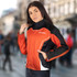 A woman wearing a black, orange, and white custom sports jacket with a logo.