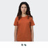 A woman stands wearing an orange TRENDSWEAR original women's T-shirt. The shirt has a simple design and a logo.