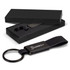 A black key ring with a leather strap and metal clip, displayed in a sleek black box.
