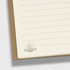 A spiral notebook with a natural brown cover and lined pages, featuring a logo at the bottom corner.
