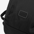 A black roll-up backpack with textured fabric and a small branded patch. The straps are visible on the side.