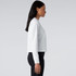 A long-sleeve white tee in a side view, featuring a relaxed fit and a logo on the chest.