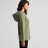 A green hoodie with a hood, featuring a front pocket, displayed from the side. It has a logo on it.