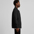 A man in a black bomber jacket stands sideways, showcasing the jacket's design and fit. The jacket has a logo.