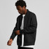 A black bomber jacket with a zip front and ribbed cuffs, worn by a person adjusting the sleeve.