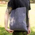 A grey RPET felt tote bag held by a person, set against a green outdoor background. The bag features a logo.