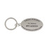A silver oval keyring with an attached ring, featuring engraved details and a logo.