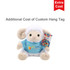 A plush sheep toy wearing a blue shirt and holding a colourful hang tag, featuring a logo.