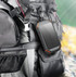 A solar-powered wireless power bank in black with orange accents, attached to a backpack.
