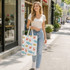 A woman holds a multi-coloured cotton tote bag featuring various marine life patterns while walking on a city street.