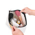 A canvas cosmetic bag in white, filled with various beauty products, including bottles and a makeup brush.