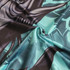 Close-up of a patterned fabric featuring shades of turquoise and black, showcasing details of a sublimated design.