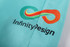 A pair of turquoise beach shorts featuring a multicoloured logo and the text "InfinityDesign."