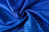 A close-up of a blue polyester spandex fabric featuring a pattern of small purple dots.