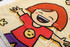 A wearable blanket featuring a cheerful cartoon character with a red shirt, yellow smiley face, and vibrant designs.