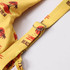 A yellow bikini top featuring a beach-themed print and an adjustable strap, with a logo detail.